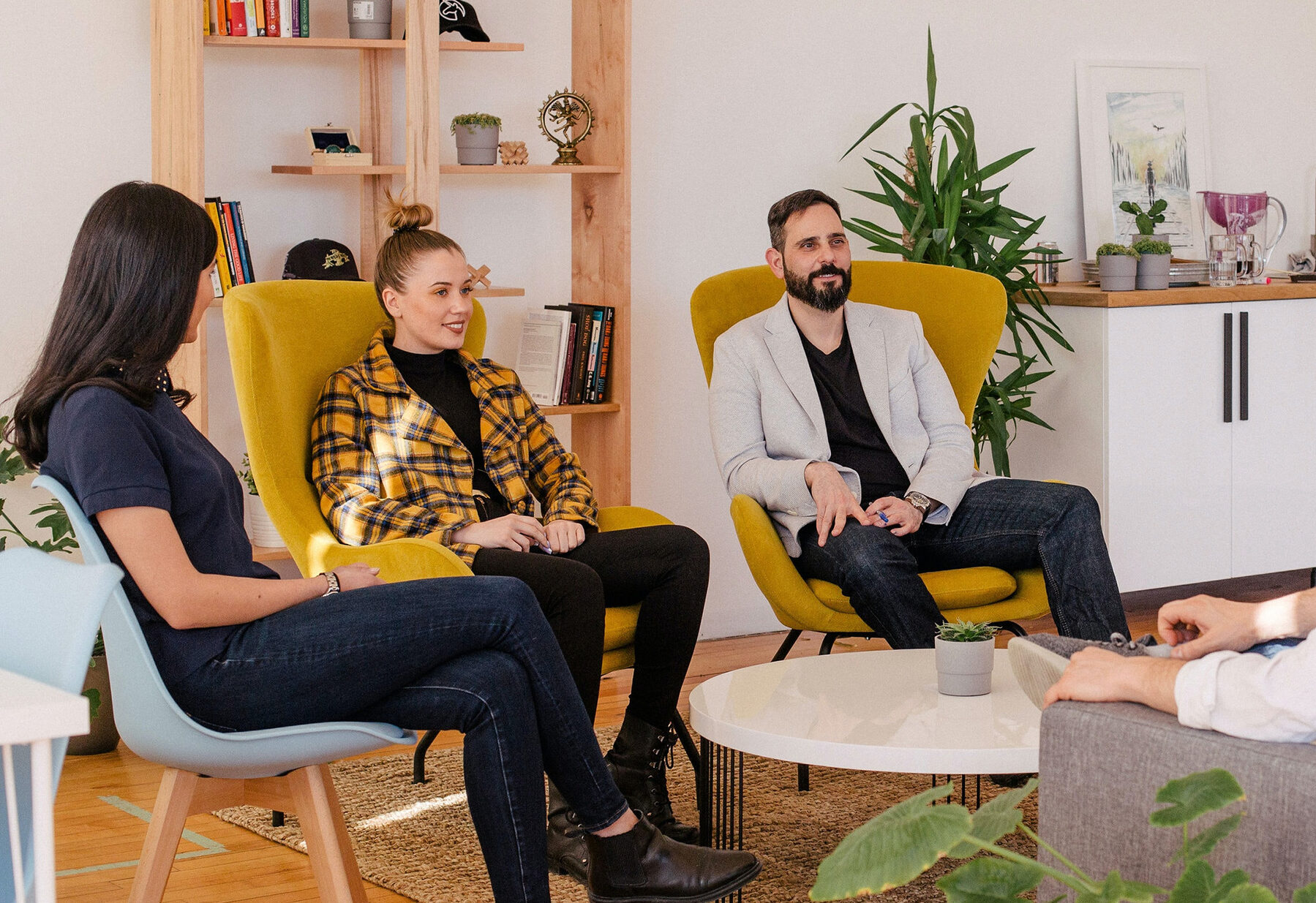 Three colleagues sat on individual yellow chairs conducting an interview with an individual out of camera shot.